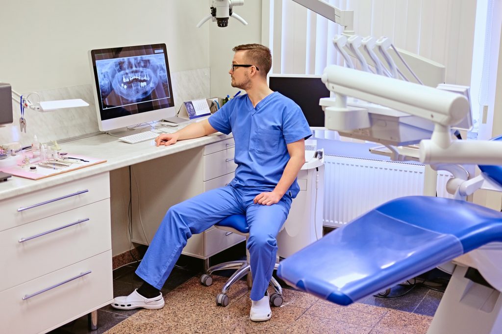 Dentist looking at teeth x-ray on the computer in a dentist office.