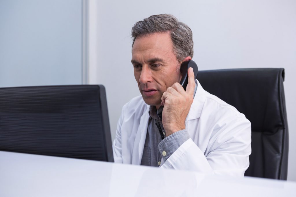 Dentist talking on phone while sitting by computer