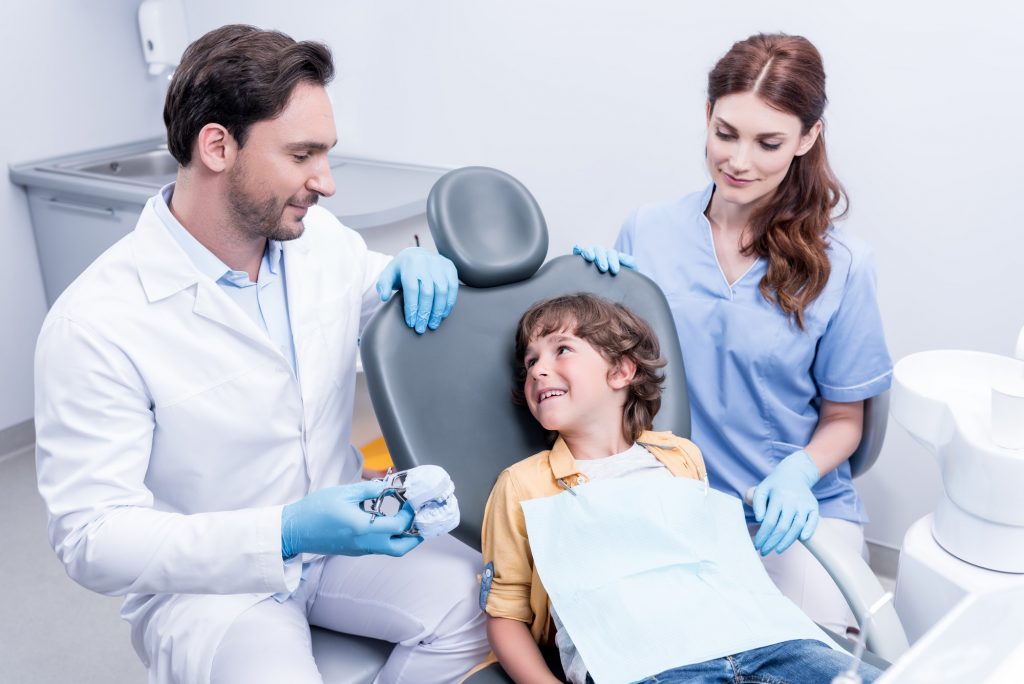 dentists preparing little boy for examining teeth at dentist office