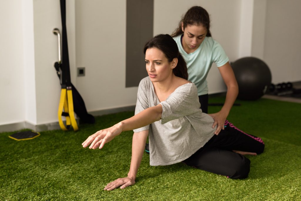 Physical therapist assisting young caucasian woman with exercise