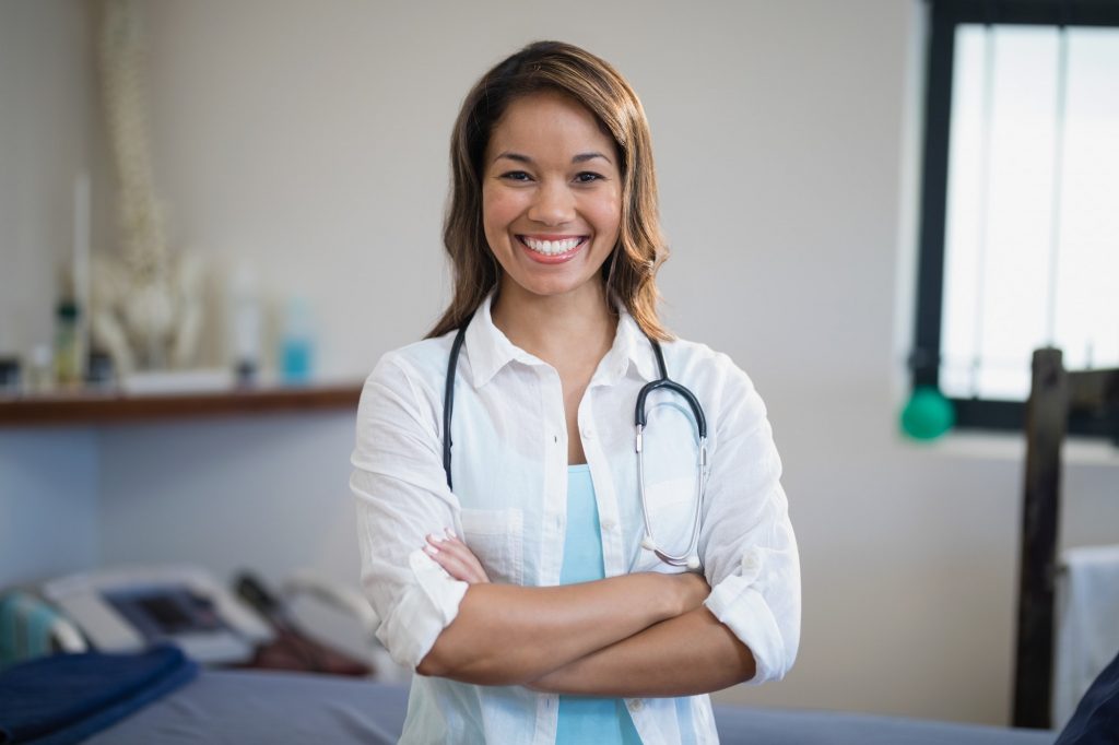 Portrait of smiling young female therapist standing with arms crossed