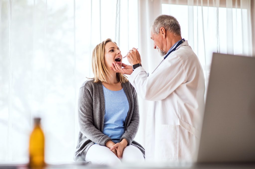 Senior doctor examining a young woman in office.