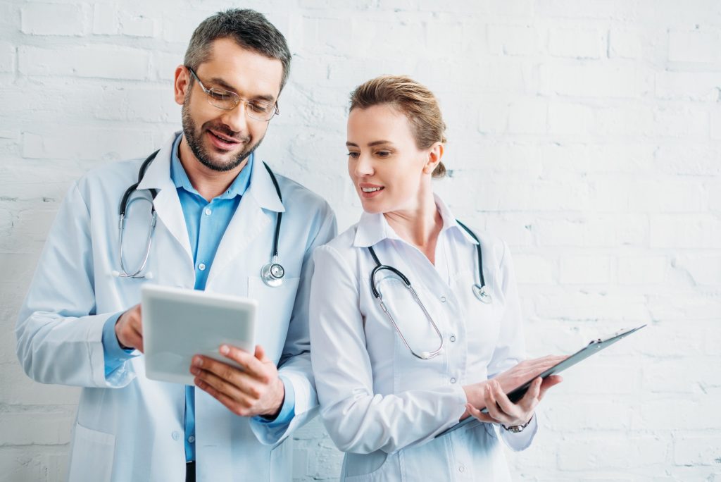 happy doctors working together with tablet and clipboard